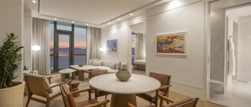 a dining room with two tables and chairs and a living room at Hyatt Regency Izmir IstinyePark in Izmir