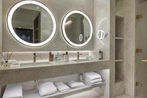 a bathroom with two sinks and two mirrors at Hyatt Regency Izmir IstinyePark in Izmir