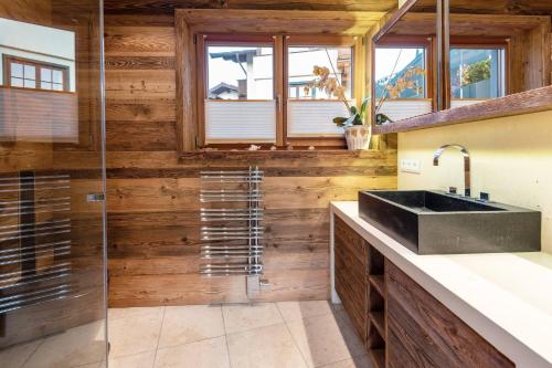 a bathroom with a sink and a glass shower at Pöllmühle Penthouse by Alpine Host Helpers in Kirchberg in Tirol
