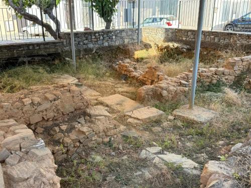 a pile of rocks in the grass next to a building at Villa GIANNAKOS MINOAN HERSONISSOS in Kastéllion