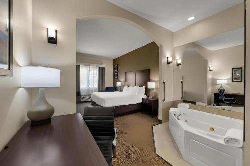 a large hotel room with a bed and a bath tub at Comfort Inn & Suites Atoka in Atoka