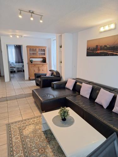 a living room with a black leather couch and a table at Appartement Confidence, Monteurwohnung in Bürstadt