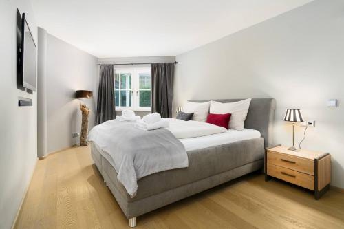 a bedroom with a bed with white sheets and red pillows at Kitz-Heart Apartments by Alpine Host Helpers in Kitzbühel
