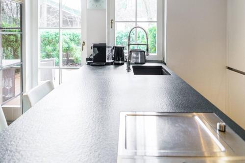 a kitchen with a counter with a sink and windows at Kitz-Heart Apartments by Alpine Host Helpers in Kitzbühel