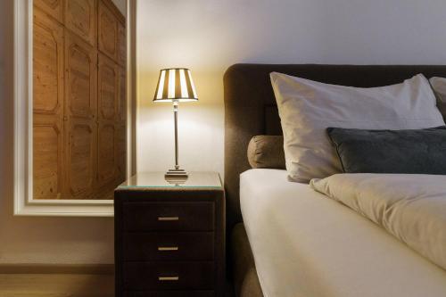 a lamp on a night stand next to a bed at Kitz-Heart Apartments by Alpine Host Helpers in Kitzbühel