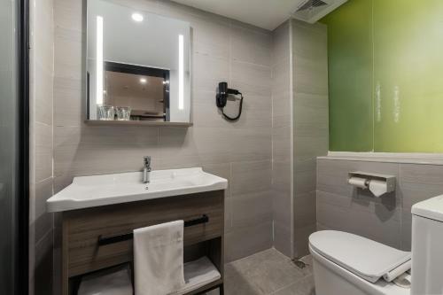 Un baño con lavabo, inodoro y espejo. en Xiangshang Hotel&Canton Fair Shuttle Bus, en Guangzhou
