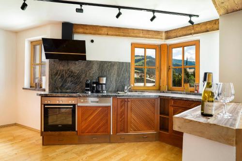 a kitchen with wooden cabinets and a counter with wine glasses at KitzAlps Apartments by Alpine Host Helpers in Kirchberg in Tirol