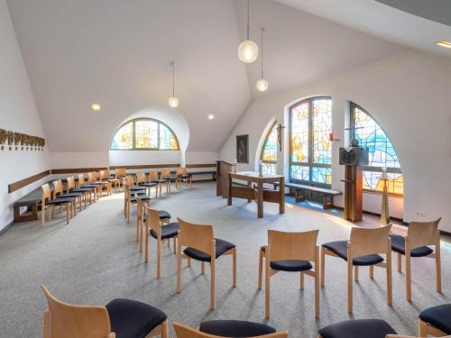 an empty church with chairs and tables and windows at Christkönigshaus in Stuttgart