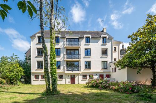 - une vue sur l'extérieur d'une grande maison blanche avec des arbres dans l'établissement Auberge Saint Thegonnec, à Saint-Thégonnec