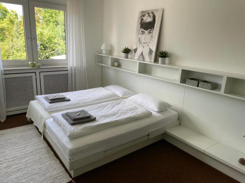 a white bedroom with a bed and a window at Messewohnung Düsseldorf in Düsseldorf