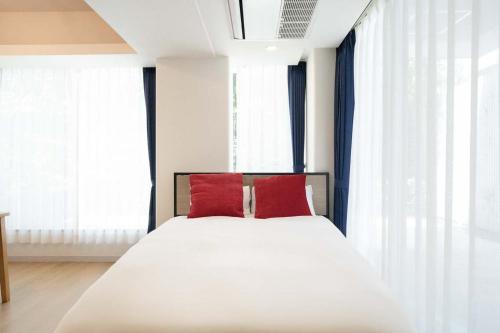 a bedroom with a white bed with two red pillows at Fujiterrace Yoga in Tokyo