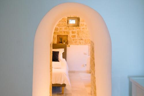 a bedroom with an archway with a bed and a mirror at Il TrullOzio in Castellana Grotte