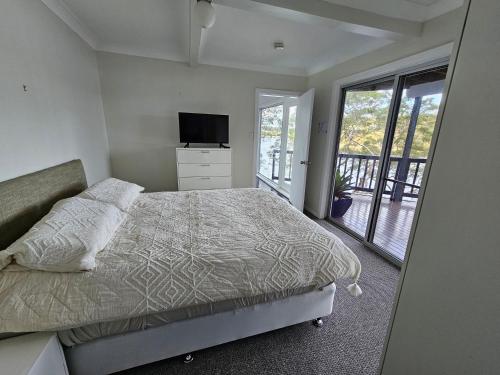 a bedroom with a bed and a television and a balcony at Breathtaking Waterfront Retreat- Studio Apartment