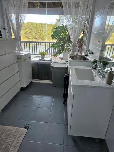 a white kitchen with a sink and a window at Breathtaking Waterfront Retreat- Studio Apartment