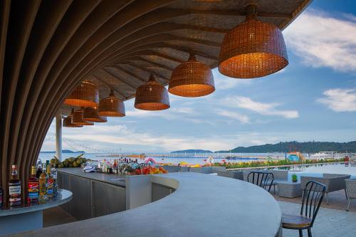 a patio with a bar with a view of the beach at Summer Bay Beach Club & Cabins Sihanoukville by Preference in Sihanoukville