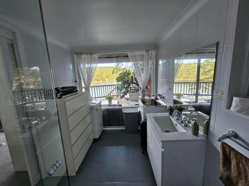 a white bathroom with a sink and a shower at Breathtaking Waterfront Retreat- Studio Apartment