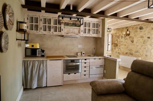 a kitchen with white cabinets and a couch in a room at Miradorio Rural Boutique Apto Tussio in Ruiloba
