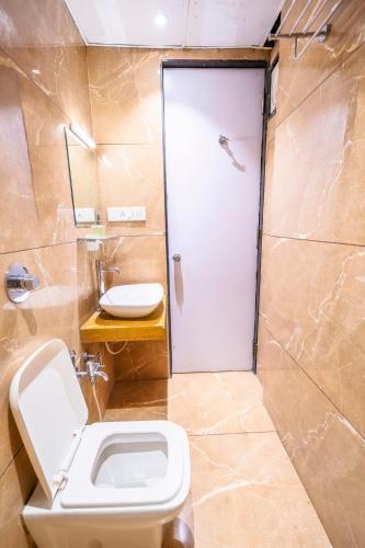a bathroom with a toilet and a shower with a door at Hotel Bhabha in Rajkot