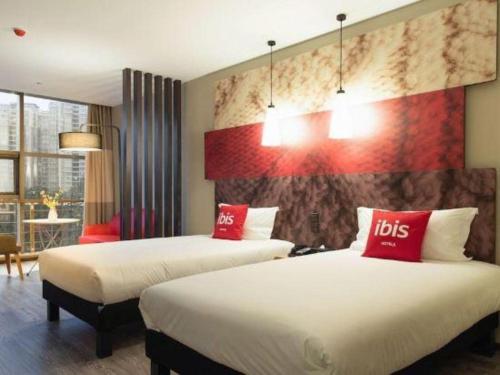 a hotel room with two beds with red pillows at ibis xian North Second Ring Weiyang Rd Hotel in Xi'an