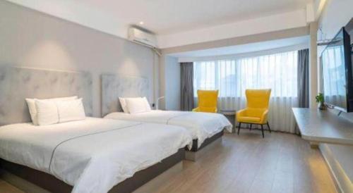 a hotel room with two beds and two yellow chairs at Magnotel Fuzhou Wuyi Road Sanfangqixiang in Fuzhou