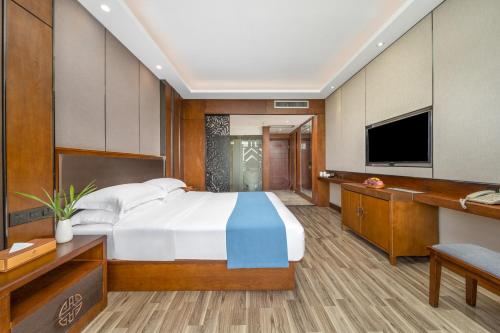 a bedroom with a large bed and a television at Lijiang Riverside Luxury Hotel, Guilin in Guilin