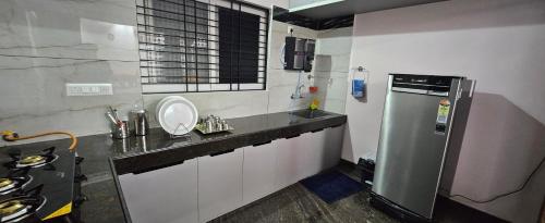 a small kitchen with a sink and a refrigerator at Home Inn in Mysore