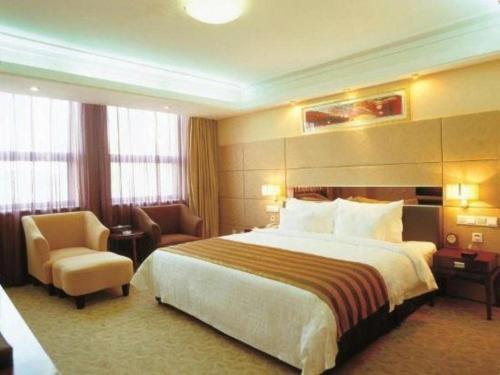 a hotel room with a large bed and a chair at Xian Union Alliance Atravis Executive Hotel in Xi'an