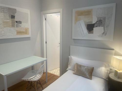 a bedroom with a white bed with a desk and a chair at Des Artistes in Barcelona