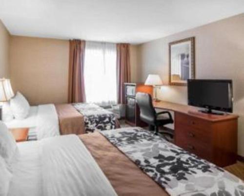 a hotel room with two beds and a desk with a television at Rodeway Inn & Suites Salina South in Salina