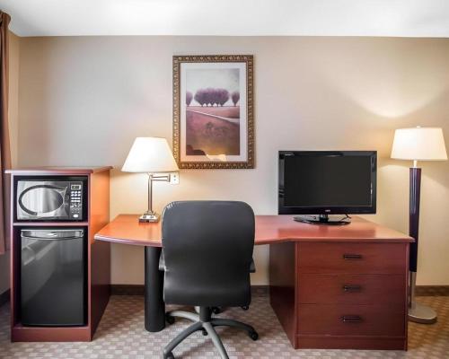 a room with a desk with a microwave and a television at Rodeway Inn & Suites Salina South in Salina