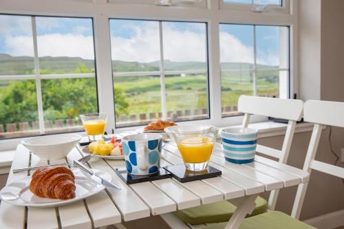 un tavolo per la colazione con succo d'arancia e croissant davanti a una finestra di Charming Isle of Skye Holiday Cottage, Glendale a Glendale