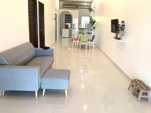 a living room with a couch and a table and chairs at Azzahra Homestay in Permatang Pauh