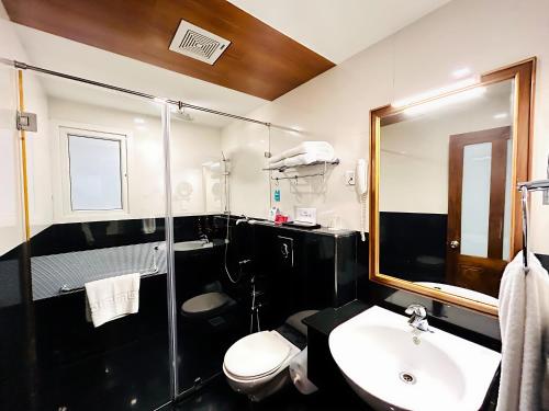 a bathroom with a sink and a toilet and a mirror at Le Maritime Kochi in Cochin