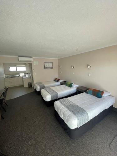 a room with three beds in a room at Kauri Court Motel and Apartments in Palmerston North