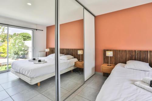 two beds in a room with orange walls at La tranquilité bleue - Maison avec Parking cloturé in Les Sables-dʼOlonne