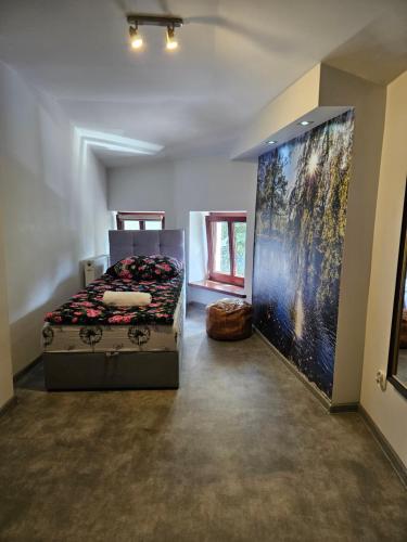 a bedroom with a bed and a large painting on the wall at Roller Hostel in Łódź
