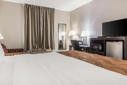 a hotel room with a large bed and a desk at Suburban Studios Mason Hwy 42 in Mason