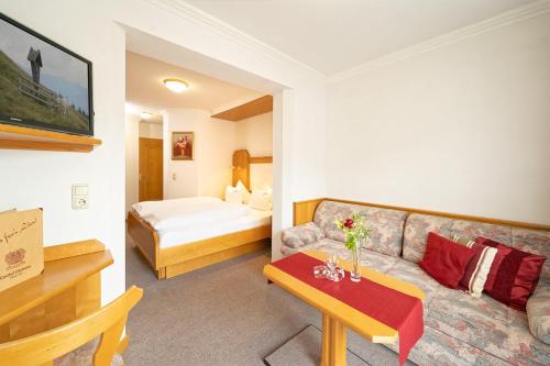 a hotel room with a couch and a bed at Hotel Edelweiss in Maria Alm am Steinernen Meer