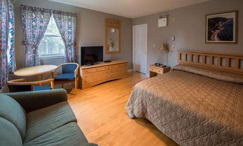 ein Schlafzimmer mit einem Bett, einem Tisch und einem Sofa in der Unterkunft Auberge Doucet Inn in Chéticamp