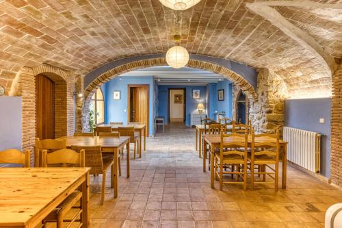 a dining room with wooden tables and chairs at Mas la Ginesta in Borrassá