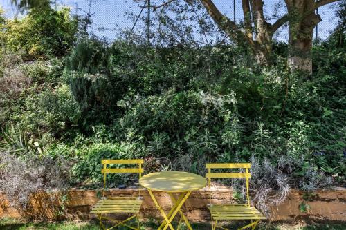 two yellow chairs and a table in front of a bush at Mas la Ginesta in Borrassá