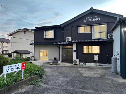 une maison noire avec un panneau devant dans l'établissement スマートハウスみづほ, à Hitoyoshi