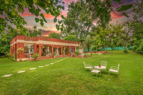 a house with a table and chairs in the yard at Hostie Tranquil Greens farmhouse near Golf course road Gurgaon in Gurgaon