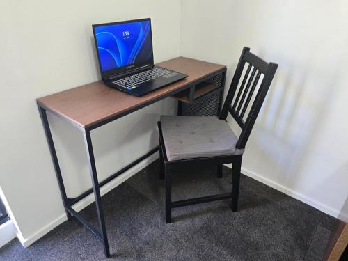 a laptop computer sitting on a desk with a chair at Apartment with Balcony near ICC On Dixon street in Sydney