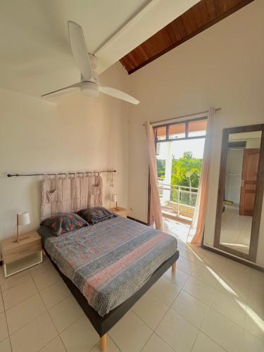 a bedroom with a bed and a ceiling fan at Magnifique Villa avec terrasse et jardin XXL in Sainte-Anne