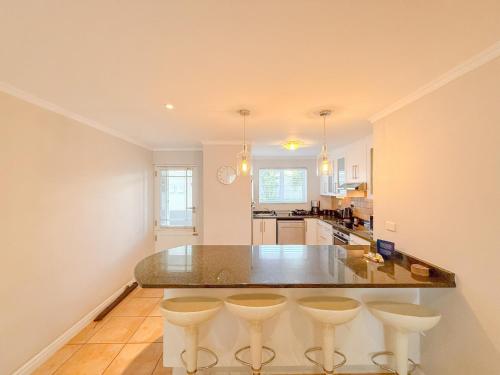 a kitchen with a large island with bar stools at Kloof Gardens: Pool Braai with Lagoon Views in Knysna