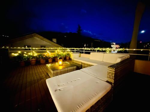 a rooftop deck with benches and lights at night at La Petite Maline friends & family in Sierre