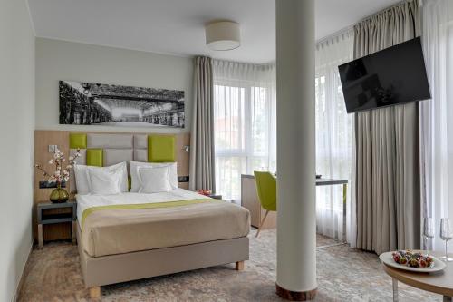 a bedroom with a bed and a desk and a tv at HOTEL ALMOND BUSINESS & SPA BY GRANO - GRANO HOTEL Gdańsk Riverside in Gdańsk