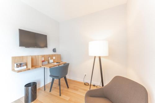 a room with a chair and a desk with a tv at Gasthof Mühle in Aesch