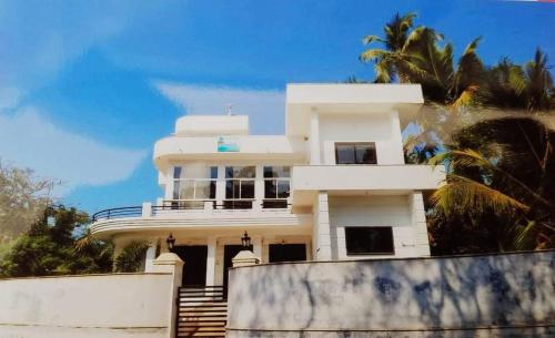 a white house with stairs and palm trees at Seawind in Kannur